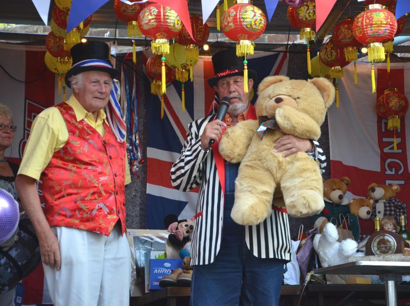Ian  Porter and Deeday White on stage at Reeves corner, auctioning a teddy bear, donated for the auction.